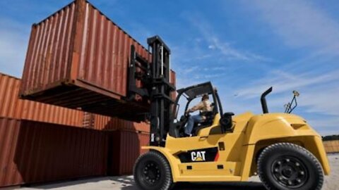 Small Forklift unloading big container from trailer.