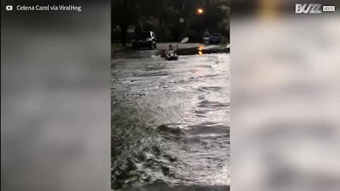 Jovem praticam caiaque na estrada depois de alagamento