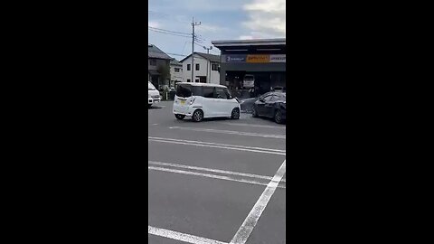 Elderly driver in Japan panics after crashing his car at a tire shop.