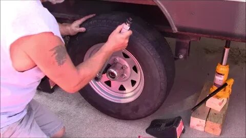 repacking the wheel bearings with fresh grease on a travel trailer