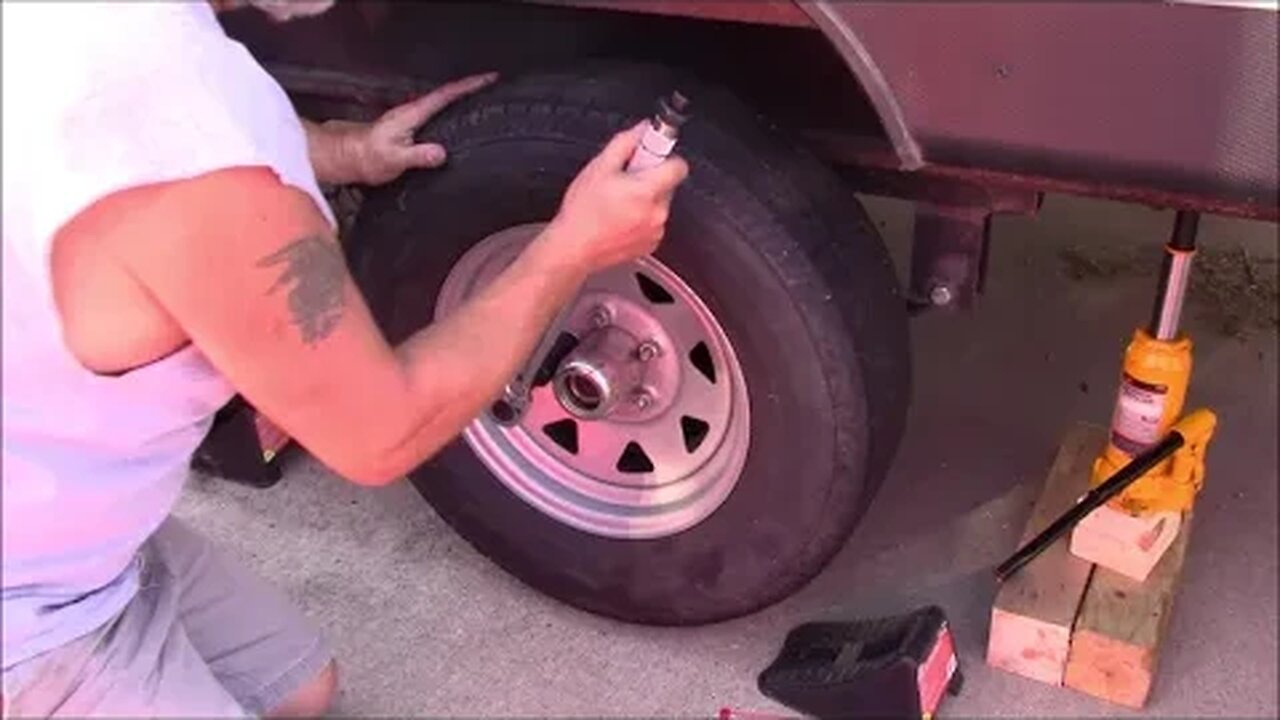 repacking the wheel bearings with fresh grease on a travel trailer