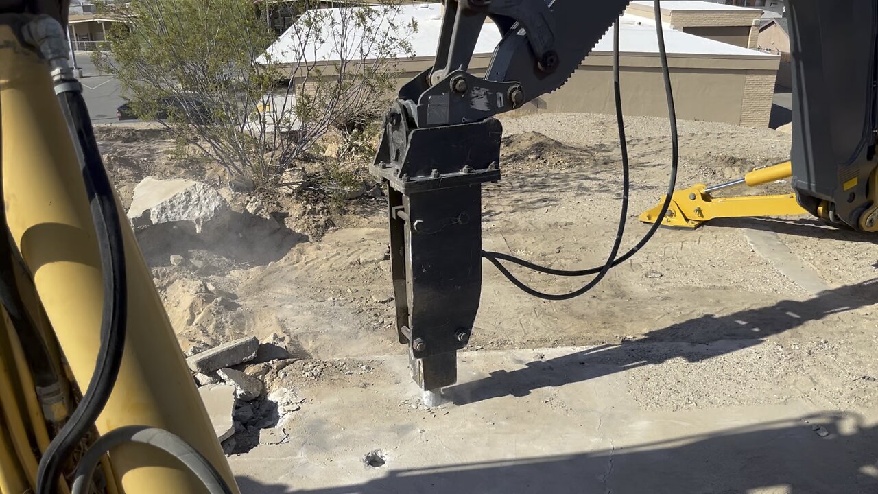 Backhoe breaking concrete