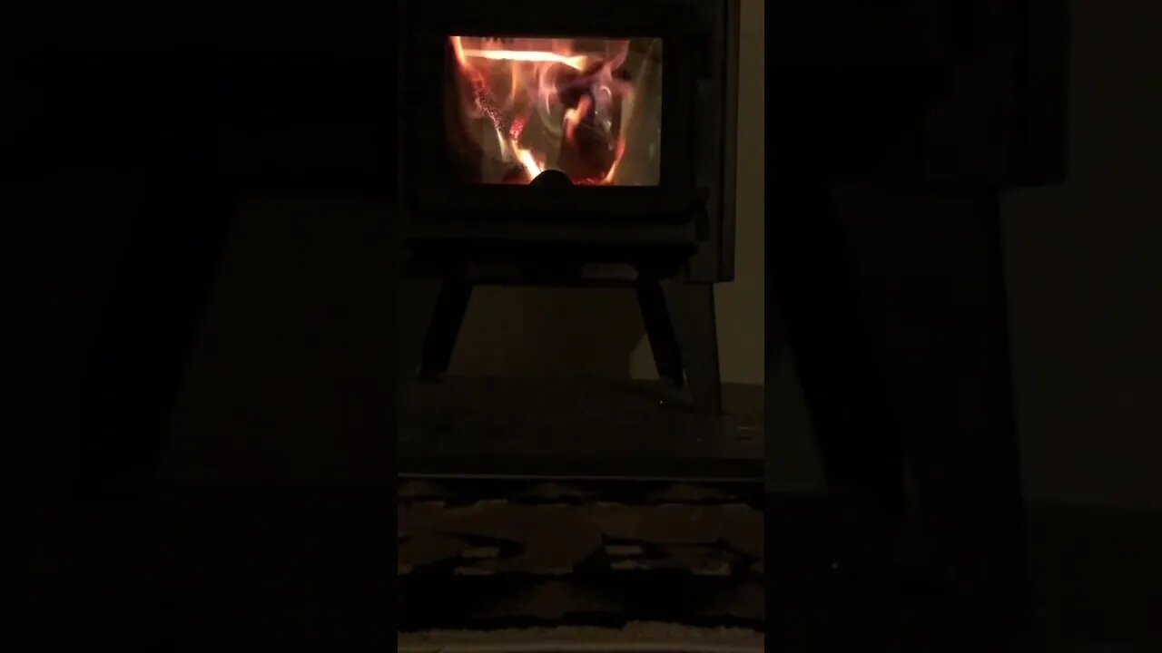 POV A person tends to their wood stove while a clock ticks in the background