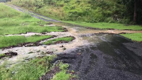 Water running over the road. Pours out through the gully