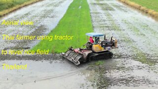 Aerial view farmer using tractor to level rice field in Thailand