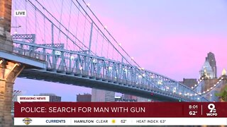 Police undergo search efforts to find a man on the run wielding a gun