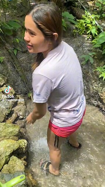 "Mountain Serenity" A young Filipina girl with long, dark hair peacefully bathing in crystal-clear