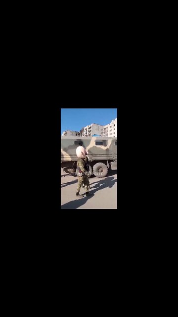 Russian soldier wears a funny costume head depicting a stereotypical Ukrainian