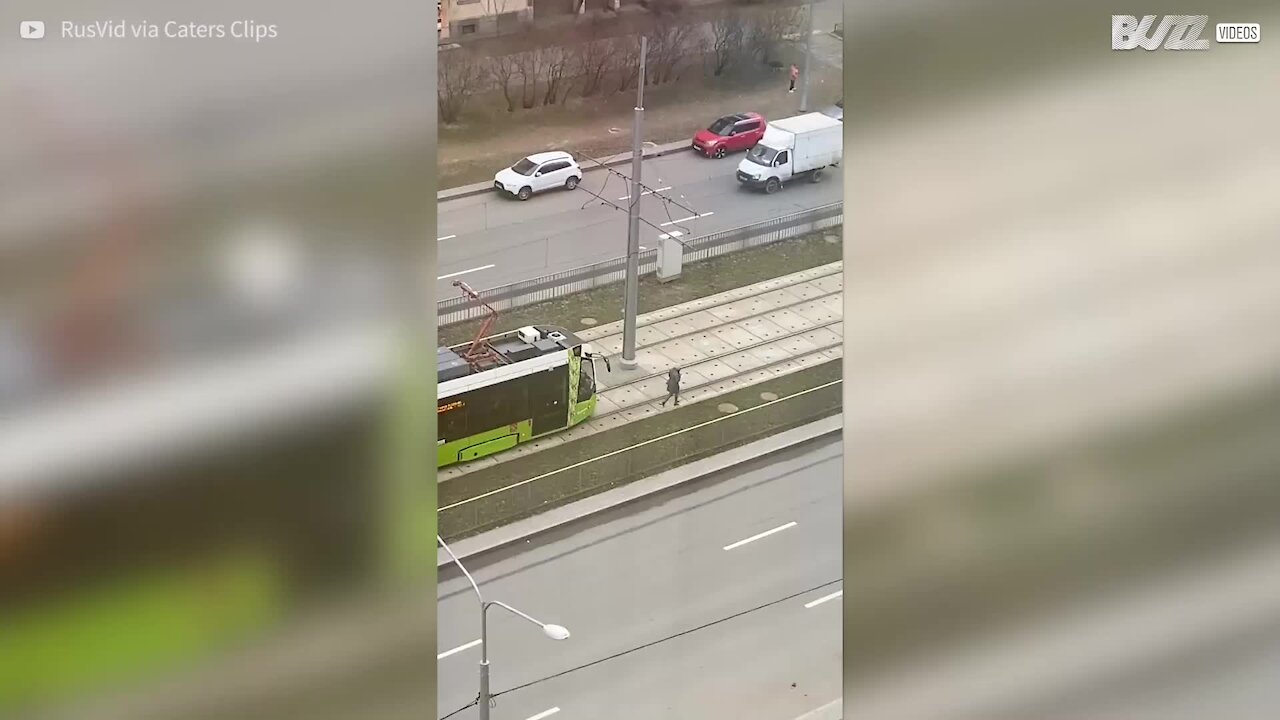 Woman with headphones in doesn't notice approaching tram