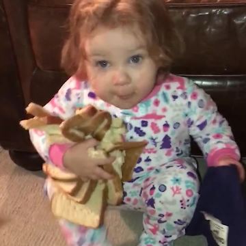 Little Girl Crawls Around Eating and Holding Onto Bread