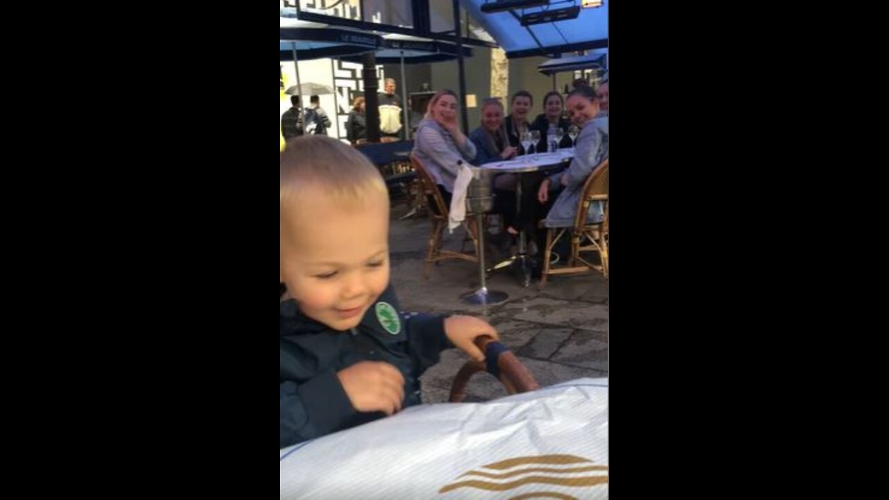 Little Boy Waves To Table Full of Young Women