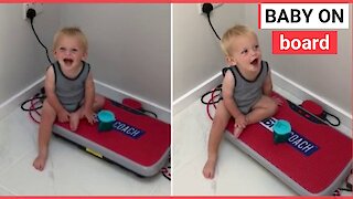 Toddler giggles as he sits on exercise board