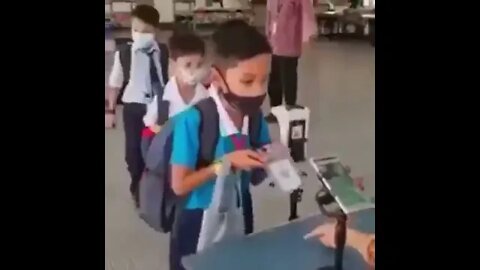 Children placing their foreheads on scanners as part of the vax pass.