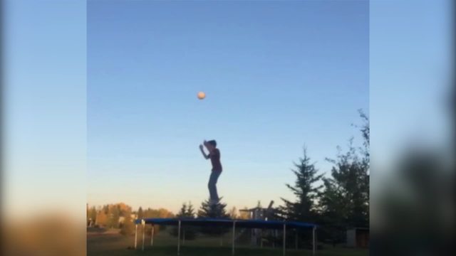 Young Boy Jumps On A Trampoline With A Ball