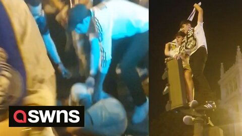 Real Madrid fans dance on the top of a set of traffic lights before smashing to the ground