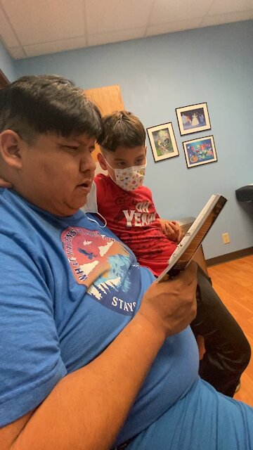 Native Dad reads to son during dr visit