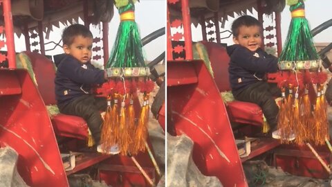 Baby preciously plays with his adorable agricultural tractor