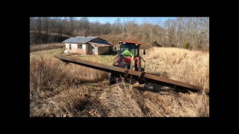 4wd compact tractor loading steel beams at Southern Illinois investment property.