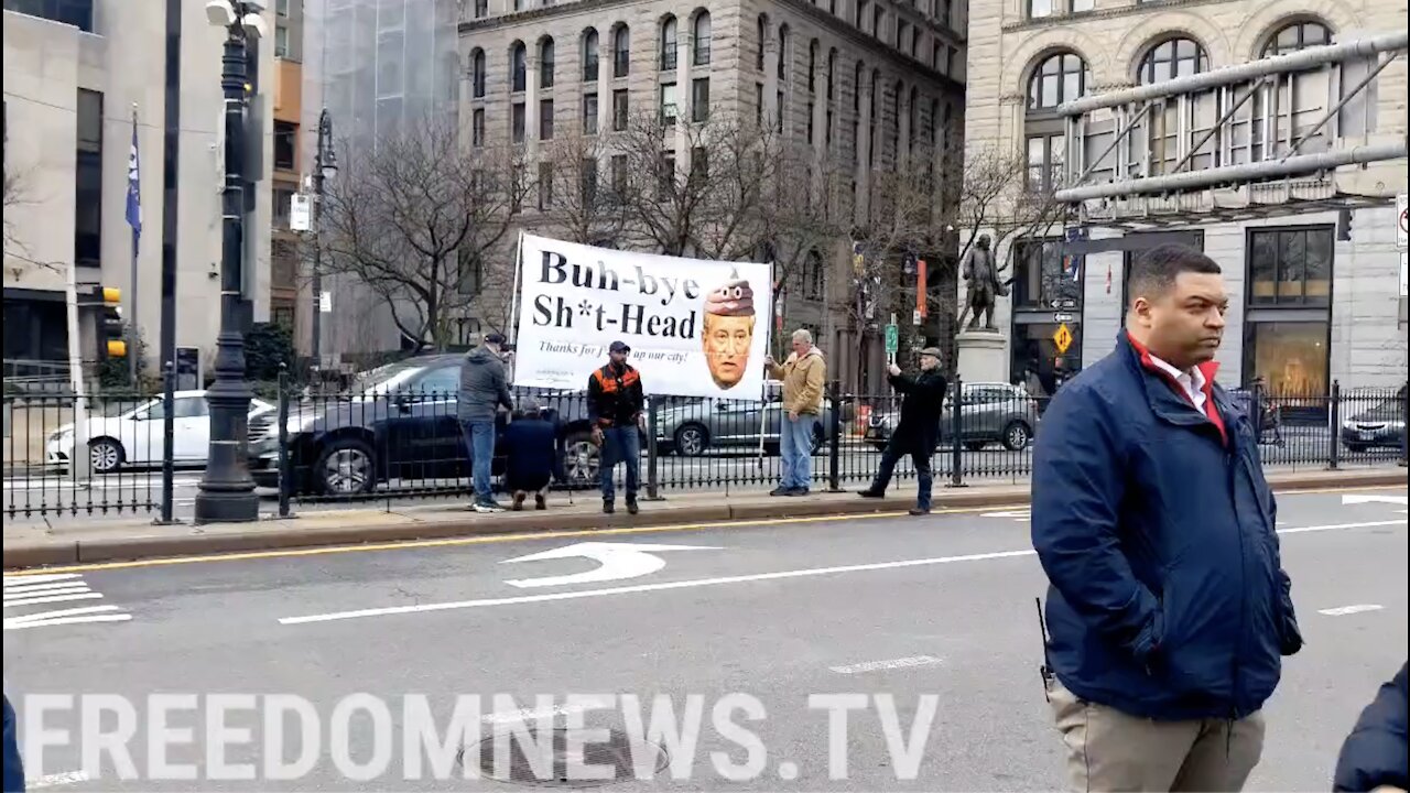 Protesters hold a sign that says "Buh-bye sh*t head" outside of City Hall where de Blasio is set to have his walkout ceremony