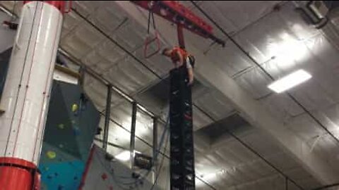 Boy shows off balancing skills by standing on huge plastic crate tower