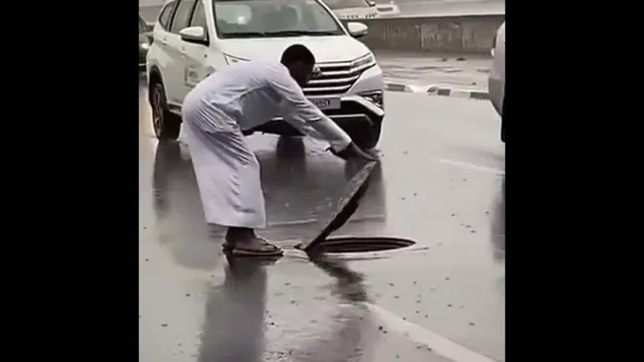 Resetting a manhole cover on a busy highway in the rain