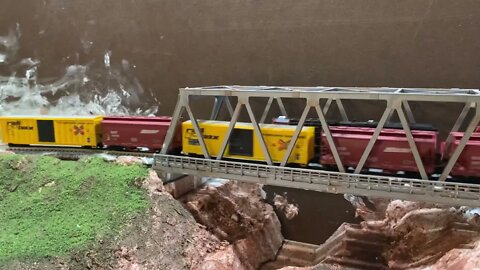 N Scale trains meeting on a bridge.