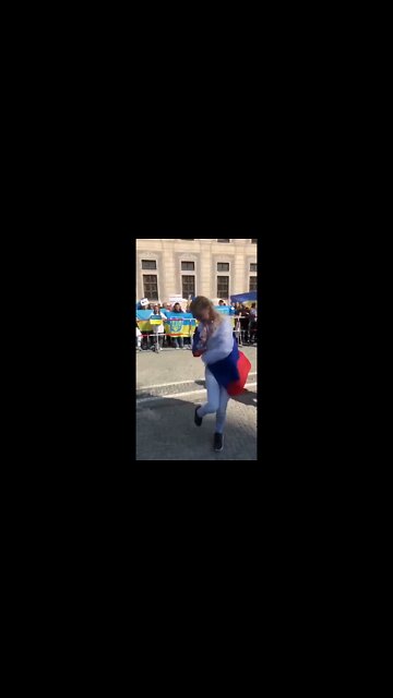 Woman with a Russian flag does a little "Kalinka" folk dance at a rally for Ukraine in Munich