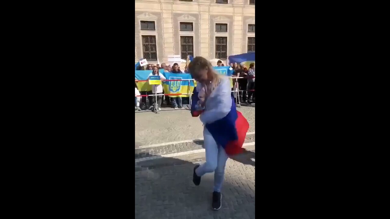 Woman with a Russian flag does a little "Kalinka" folk dance at a rally for Ukraine in Munich