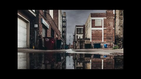 Heavy rain hitting a puddle in an industrial alley