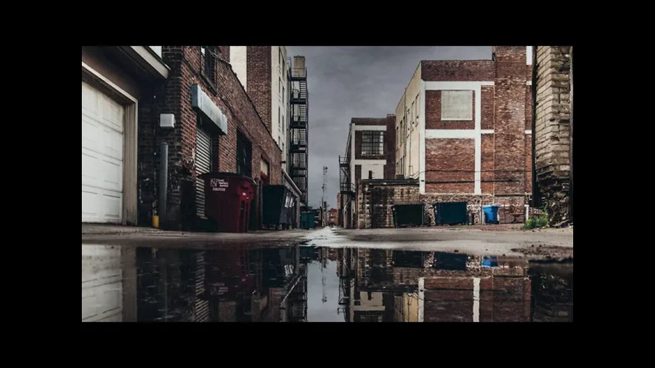 Heavy rain hitting a puddle in an industrial alley