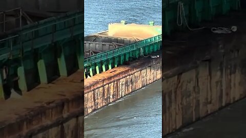 Tug boat hauling big Lafarge rock storage container going under bridge
