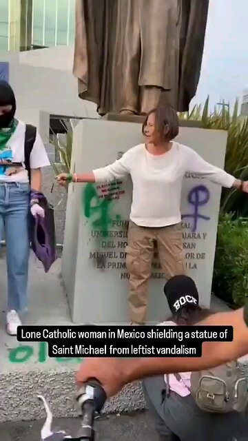 Far left activists surrounds Christian woman trying to protect a statue of archangel Michael.