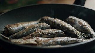 Homemade seafood dinner. Seasoning fried sardines with salt