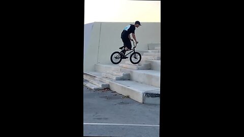 dude rides up the stairs on his front wheel