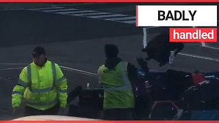 Man films baggage handlers throwing luggage onto a cart