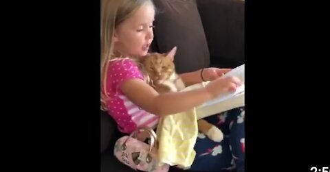 Little girl reading aloud to her cat 🤣