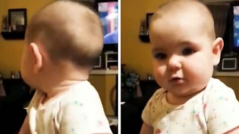 Baby looks at the camera and tries to reproduce what his mother says to him