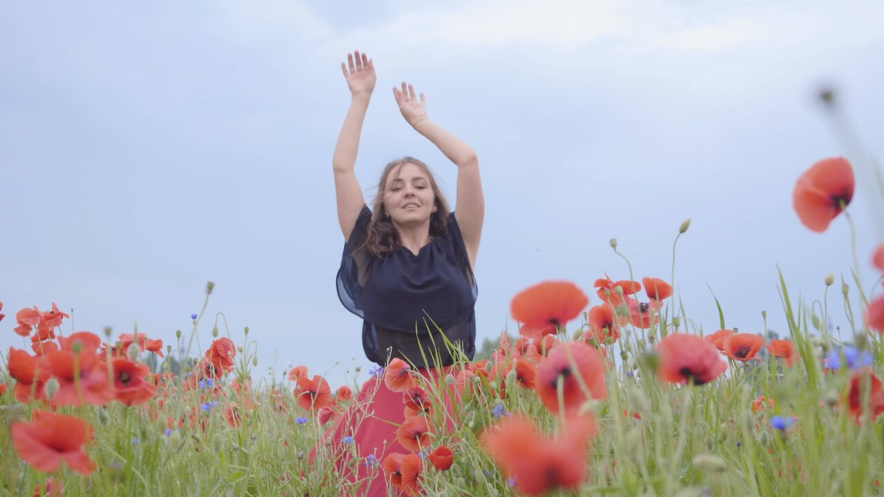 Girl dancing happily in a field of flowers.
