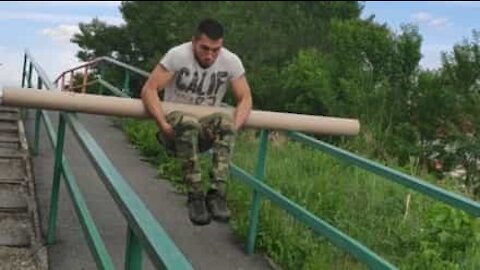 Guy somersaults down stairs using a piece of piping