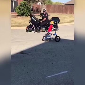 Police Officer on Motorcycle and Little Boy on Bike Circle Each Other