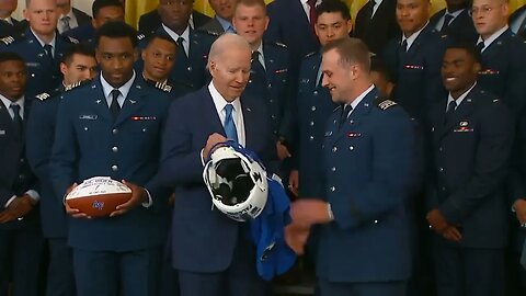 Biden Asks Airman If He Can Hold The Helmet Being Presented To Him By Air Force Football Team