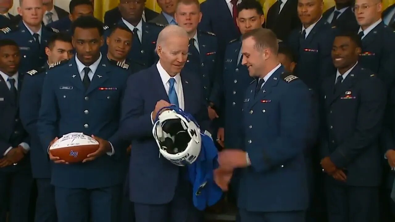 Biden Asks Airman If He Can Hold The Helmet Being Presented To Him By Air Force Football Team