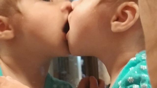 Sweet baby shares kisses with her reflection