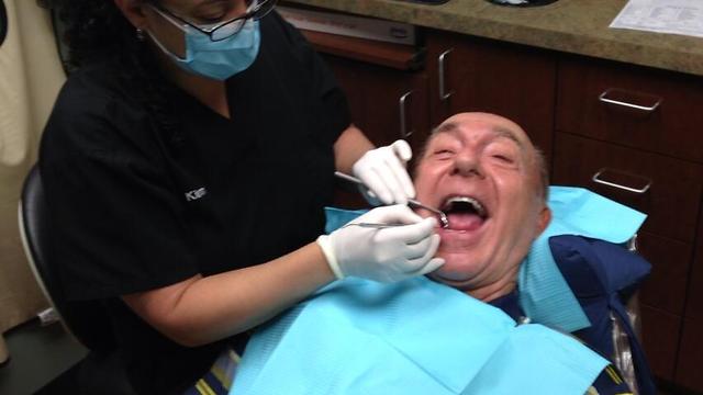 Boy films his father at the dentist.