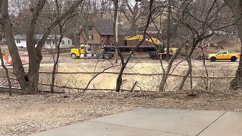 Excavator Ripping up Road & Loading Side Dump Rig. Road Construction Project.