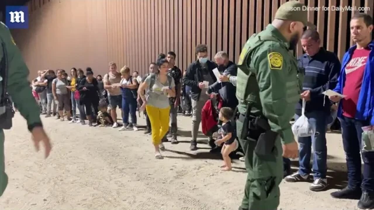Video: Migrants wait along border of containers for buses in Yuma