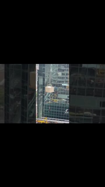 Man Holds on for dear life from a Crane by Skyscraper