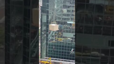 Man Holds on for dear life from a Crane by Skyscraper