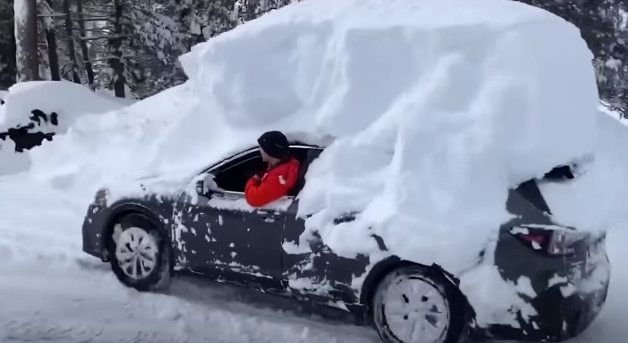 Guy has a lot of snow on car.