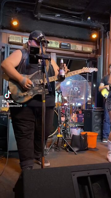 Man drinks beer while playing guitar